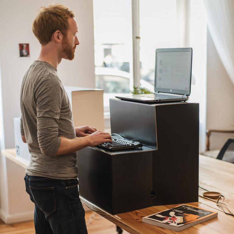 Person using a standing desk in front of computer